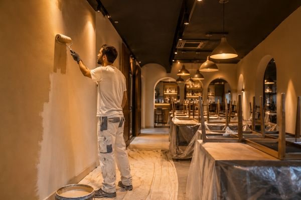 Pintor pintando la pared de un restaurante en Calafell antes de la apertura